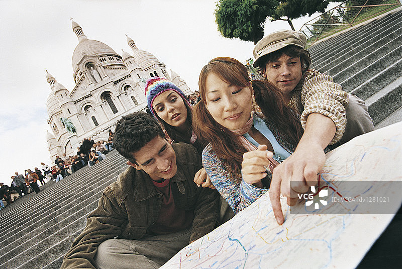 年轻的游客夫妇坐在圣心大教堂的台阶上，指着地图，法国巴黎蒙马特图片素材