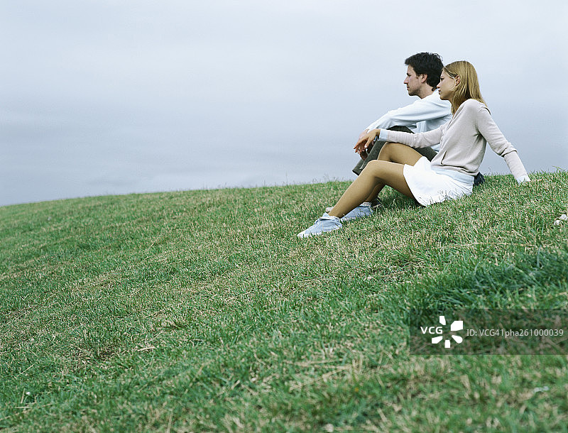 一对夫妇坐在草地上遥望远方图片素材