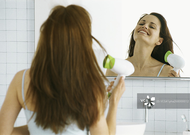 一个女人在镜子前吹头发图片素材