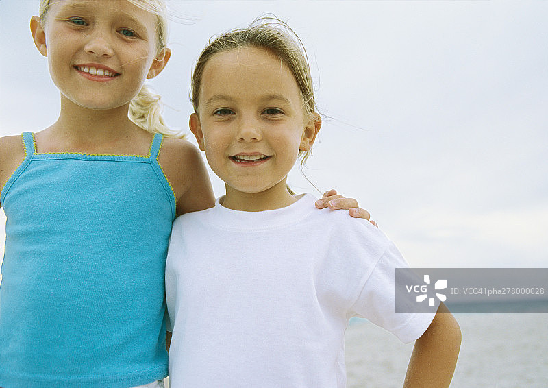 两个小女孩在海滩上并肩站着图片素材