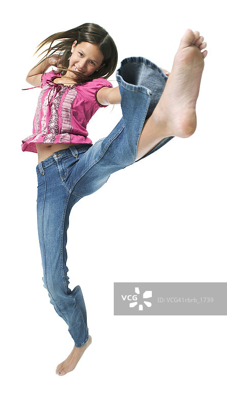 一个穿着牛仔裤和粉红色衬衫的少数民族少女跳起来，在空中踢来踢去图片素材