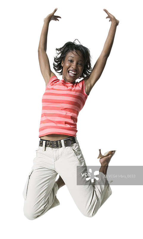 全身拍摄的一个年轻的成年女性在条纹衬衫，她跳向空中图片素材