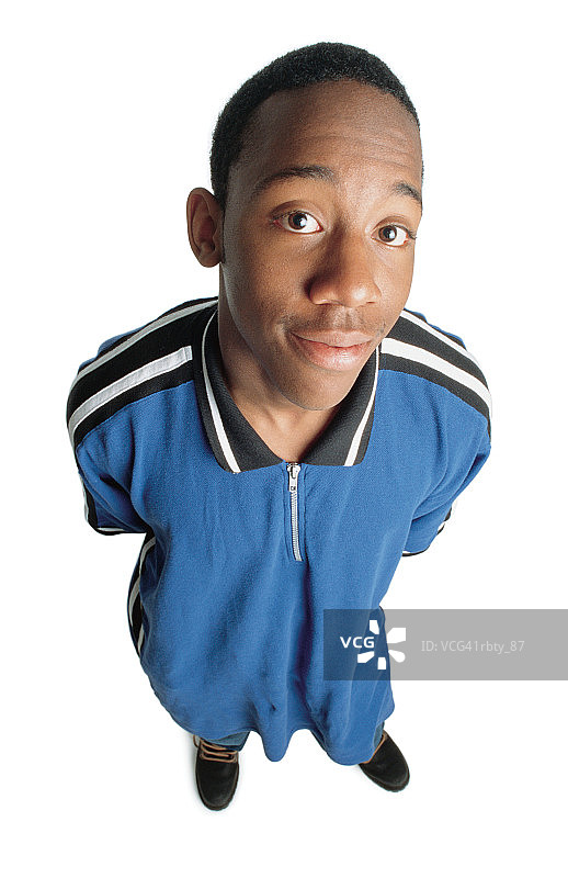 一位黑发的非裔美国男子，穿着黑色工作靴和蓝色衬衫，双手放在背后，微笑着看着镜头图片素材
