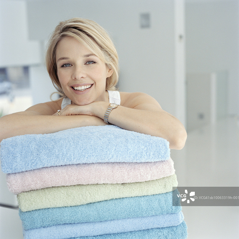 女人靠在一堆毛巾上，微笑着，肖像图片素材