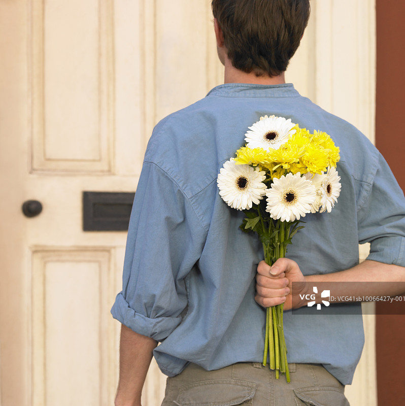 身后手持一束鲜花的男子，站在门口，后视镜图片素材