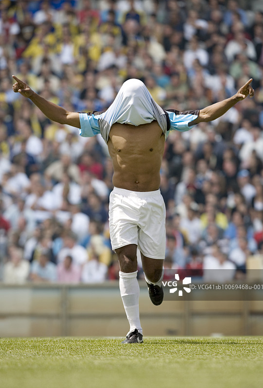男足球运动员头顶着球衣，在体育场庆祝图片素材