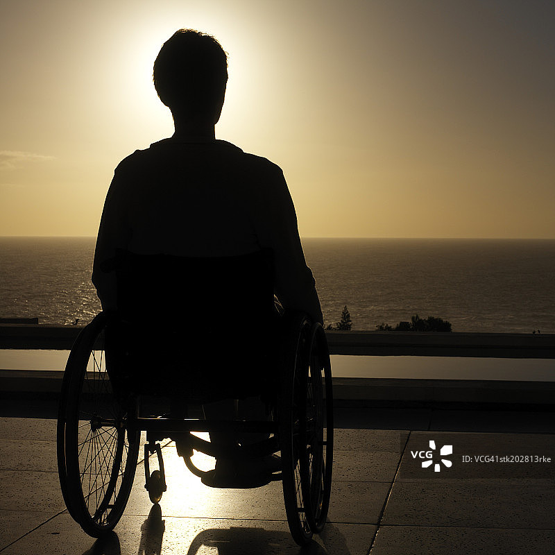 一个坐在轮椅上望向大海的人的剪影图片素材