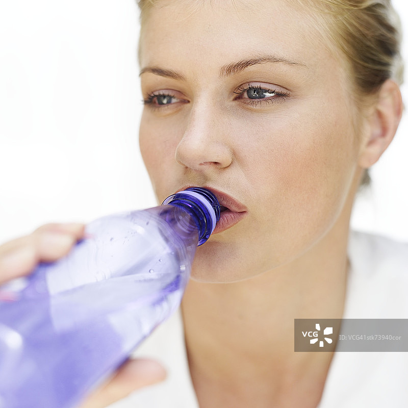 一个女人从瓶子里喝水的特写图片素材