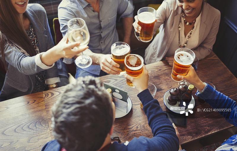 俯瞰朋友们在酒吧的餐桌上庆祝，举杯互敬啤酒图片素材
