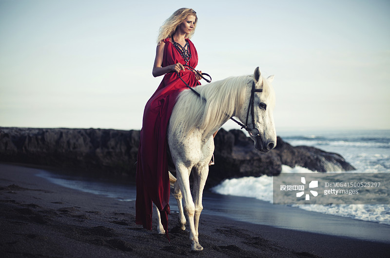 女人骑着马沿着海滩图片素材