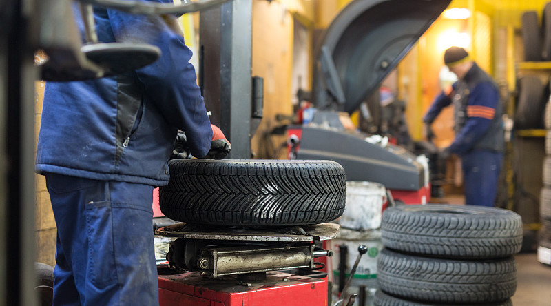 专业的汽车修理工在汽车修理服务中更换轮胎。图片素材