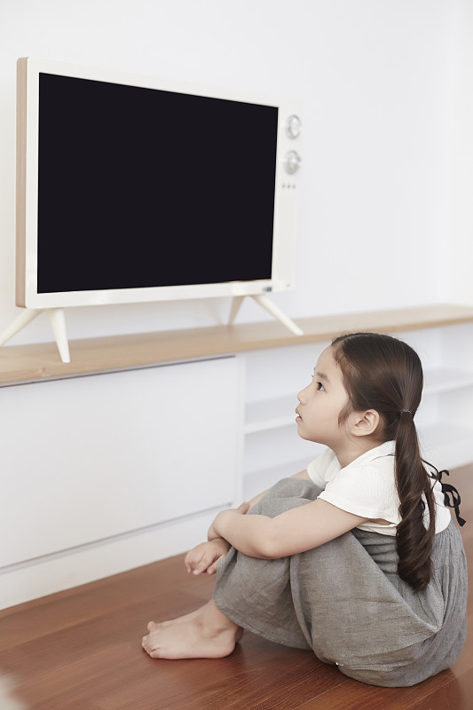 小女孩坐着看电视的照片摄影图片下载