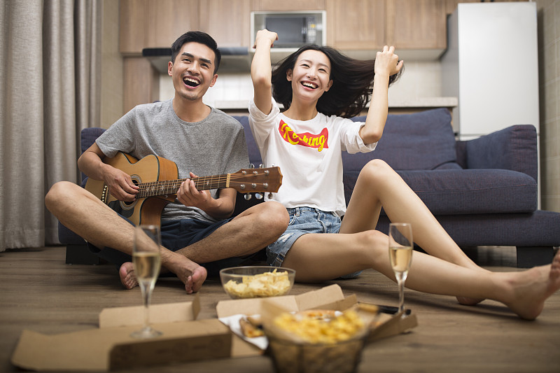 快乐的情侣在客厅演奏吉他图片下载
