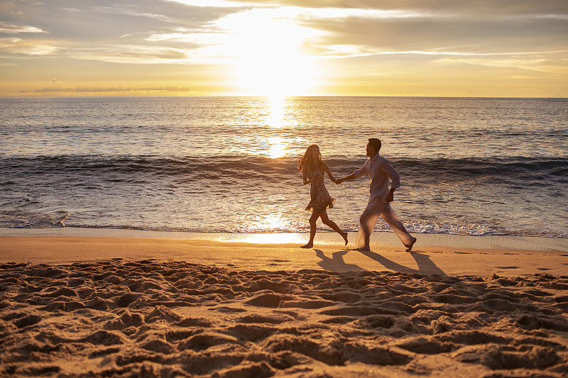 快乐的年轻夫妇在沙滩奔跑图片素材