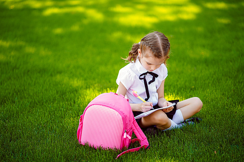 Bingo小女孩的粉红色背包坐在草地上课后图片素材
