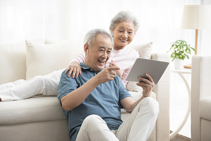 快乐的老年夫妇在客厅使用平板电脑图片素材