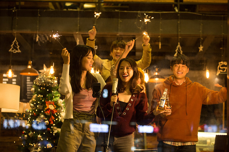 五个青年男女一起在咖啡馆放烟花唱歌庆祝平安夜和圣诞节图片下载