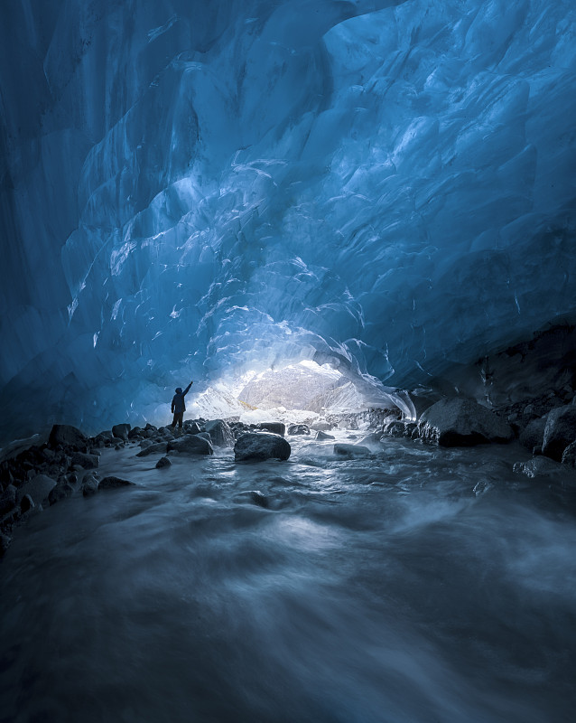 阿拉斯冰川天蓝冰洞中站立的一个人图片下载