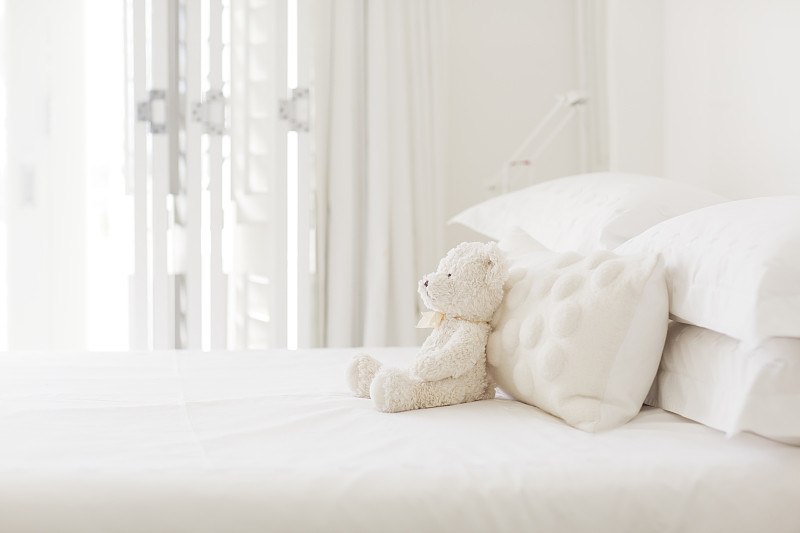 白色的床上有泰迪熊和枕头图片下载