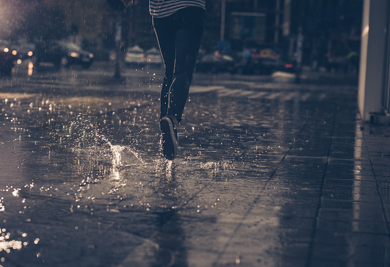 一个不认识的人在雨中奔跑的背影。图片下载