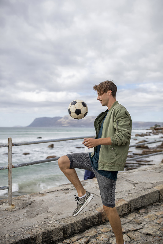 年轻人在海边平衡足球图片下载
