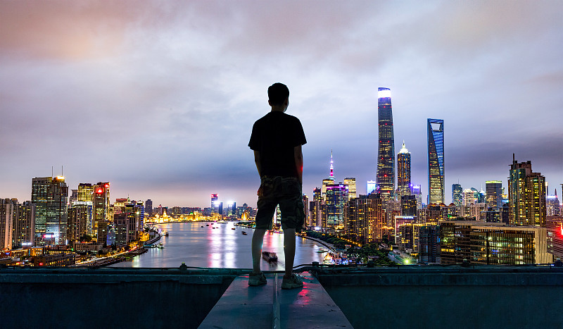 年轻人站在屋顶上，看着上海中央商务区图片下载