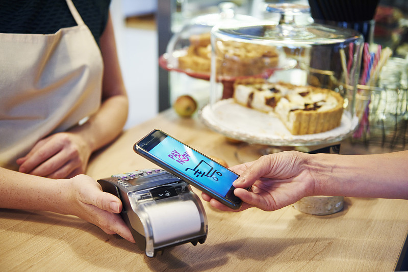 顾客在咖啡馆用智能手机支付无现金图片素材