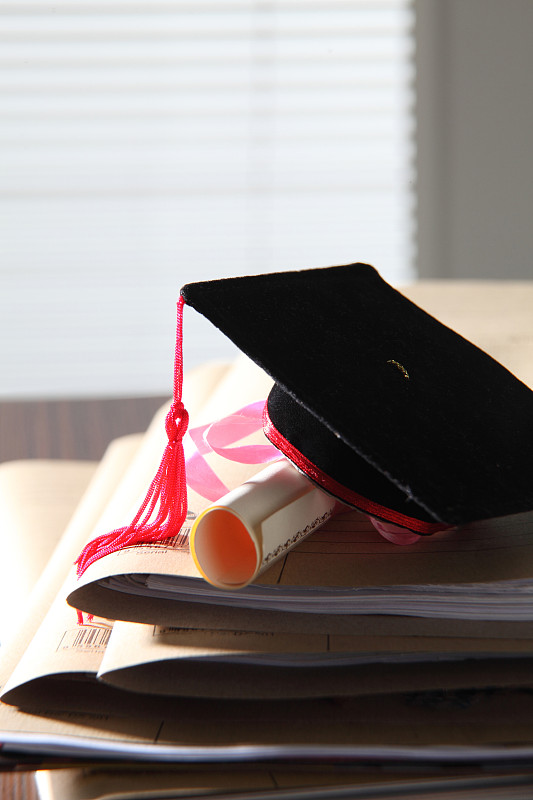 桌子上有学位帽和证书的书的特写图片素材