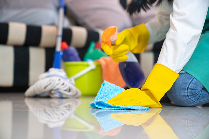 丈夫的家务和清洁概念，快乐的年轻妇女戴着蓝色橡胶手套，用喷雾和抹布擦拭灰尘，同时清洁地板在家里图片下载
