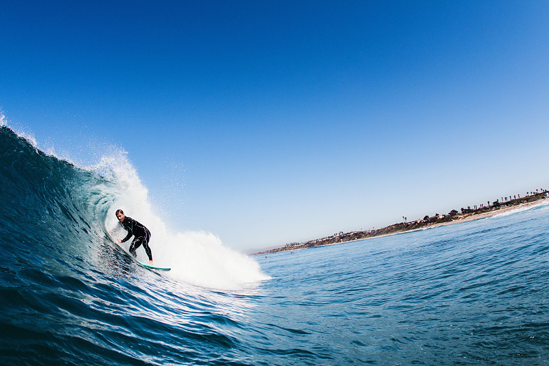 中年男性冲浪者冲浪弯曲的波浪，卡尔斯巴德，加利福尼亚州，美国图片素材