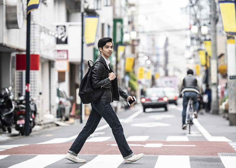 20多岁的酷日本男人在斑马线上过马路图片下载