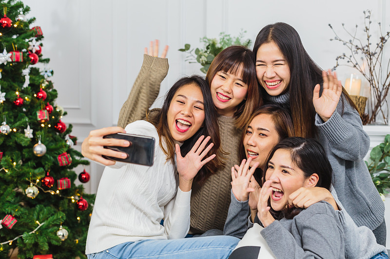一群快乐的女性朋友在家里用手机自拍图片下载