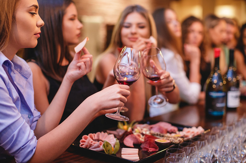 年轻的女士们喝着红酒，吃着开胃熟食图片素材