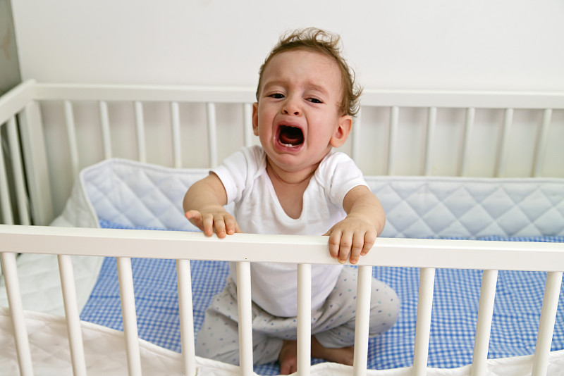 小男孩在婴儿床里哭图片下载