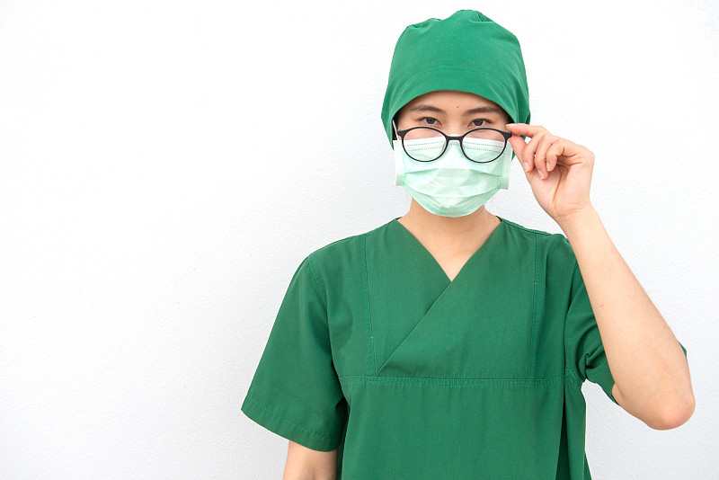 年轻自信的亚洲护士身穿外科医生制服，戴着外科口罩以防止吸入空气中的细菌或病毒疾病。图片素材