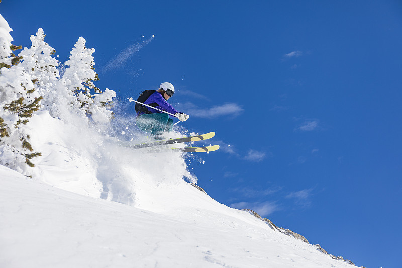 在西班牙比利牛斯山脉加泰罗尼亚巴奎拉贝雷特滑雪的一天，妇女在深雪中跳跃图片下载