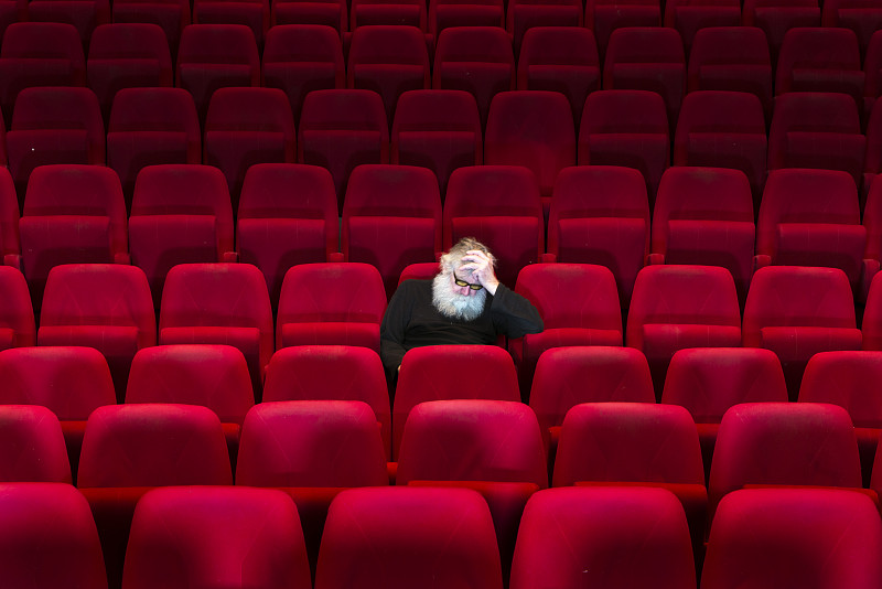 一个留着白胡子的男人坐在空荡荡的电影院，睡着了图片下载