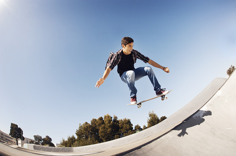低角度的人表演特技在滑板公园对清澈的蓝色天空图片下载