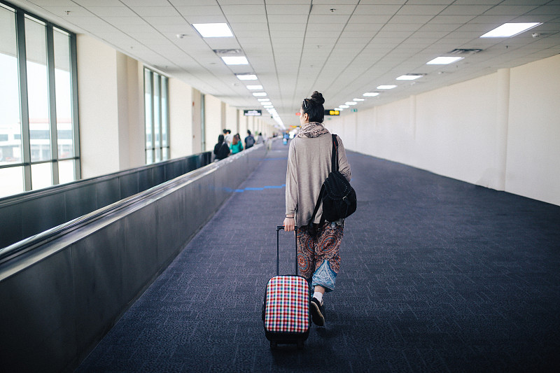 泰国甲米机场，一名年轻女子带着行李箱独自旅行图片下载