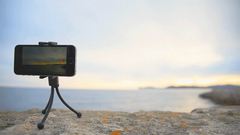 小三角架上的手机，拍摄日落时的海景视频图片下载