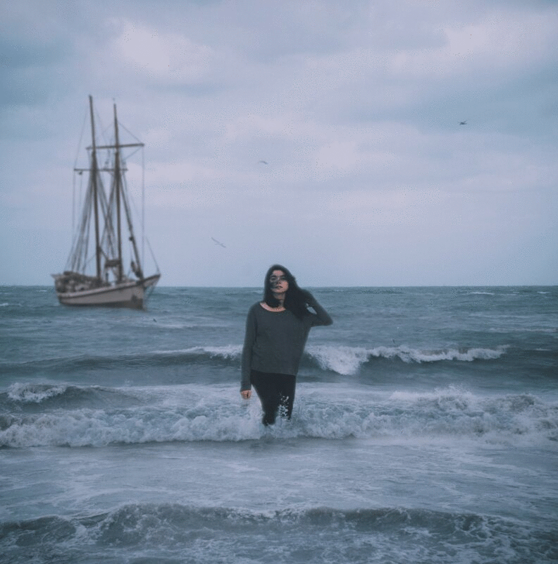 风暴后从海洋中浮现的女人的概念肖像，背景中的帆船图片下载
