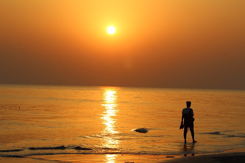 夕阳下，一个人在海滩上散步的剪影图片素材