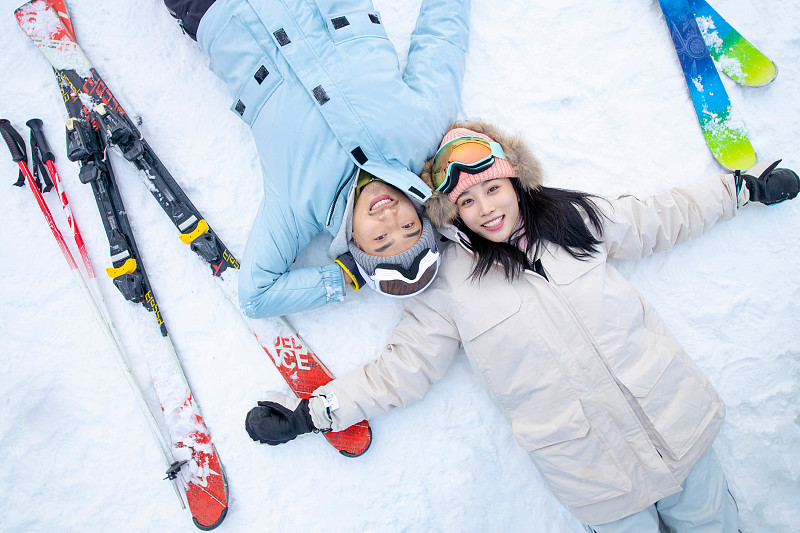 快乐的青年伴侣躺在雪地上图片下载
