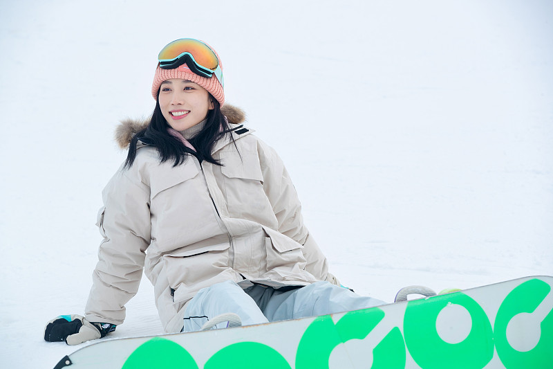 踩着单板坐在雪地上的青年女人图片素材