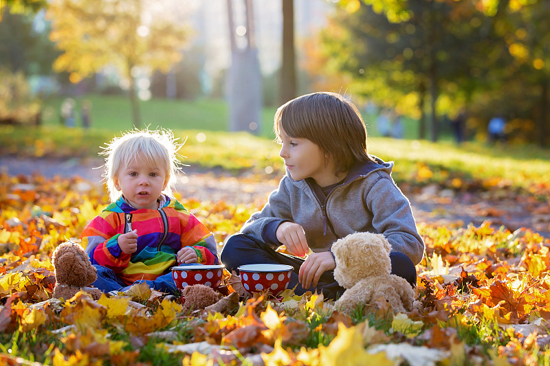 两个孩子在落叶中吃饭图片素材