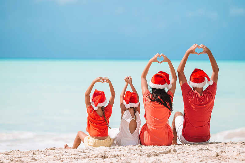 一家人戴着圣诞老人帽在热带海滩上图片素材