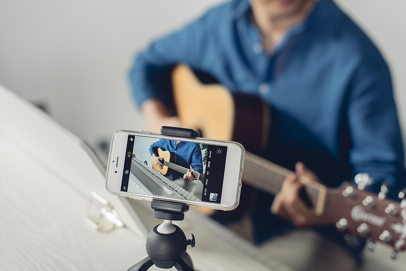 男子为个人媒体拍摄视频弹吉他的照片摄影图片下载