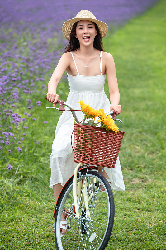 青年女人在花海里骑自行车图片下载