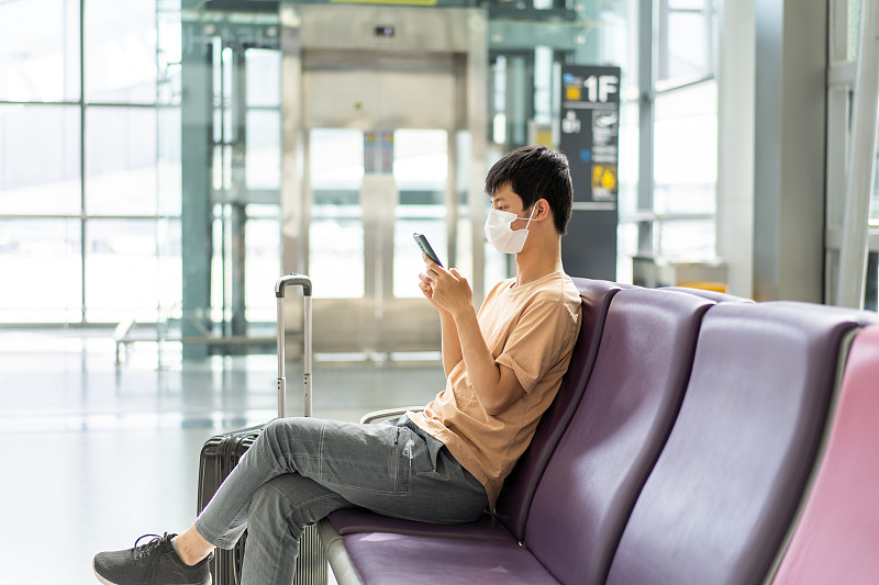 戴着口罩在机场候机的独自旅行者图片下载