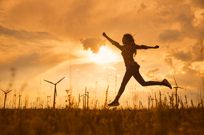 年轻女子在草原的夕阳下奔跑图片下载